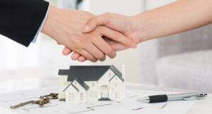 A real estate agent and home buyer shake hands.